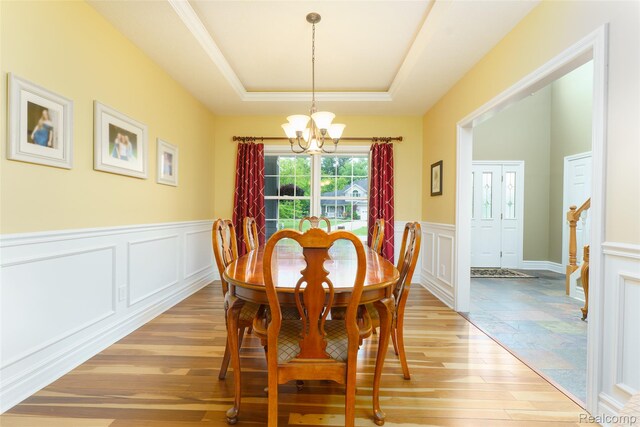 1235 Joann Ln, Williamston, MI 48895 - dining room with a chandelier, light wood-style floors, a raised ceiling, a decorative wall, and a wainscoted wall