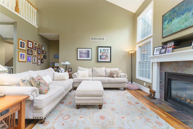 1235 Joann Ln, Williamston, MI 48895 - living area featuring high vaulted ceiling, wood finished floors, a tiled fireplace, and baseboards