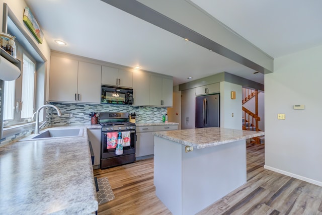 4470 Peach Ridge Ave NW, Grand Rapids, MI 49544 - kitchen featuring stainless steel appliances, a sink, light countertops, decorative backsplash, and light wood-style flooring