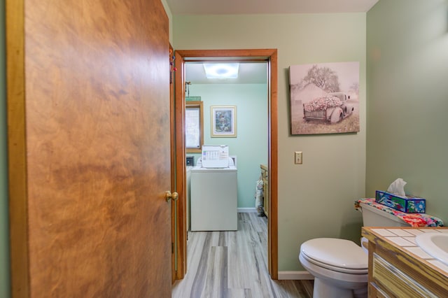 4470 Peach Ridge Ave NW, Grand Rapids, MI 49544 - half bathroom with washer and clothes dryer, vanity, toilet, wood finished floors, and baseboards