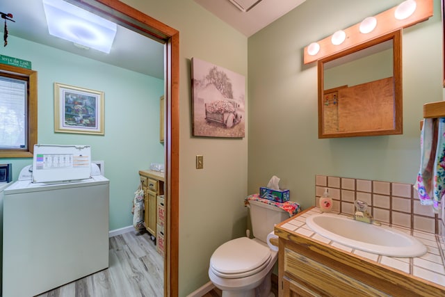 4470 Peach Ridge Ave NW, Grand Rapids, MI 49544 - bathroom featuring washer / dryer, vanity, toilet, wood finished floors, and baseboards