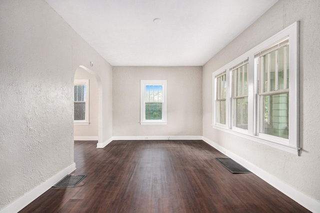 415 Cutler St SW, Grand Rapids, MI 49507 - unfurnished room with dark wood-style floors, a textured wall, baseboards, and arched walkways
