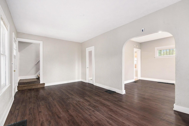415 Cutler St SW, Grand Rapids, MI 49507 - unfurnished room with arched walkways, dark wood finished floors, baseboards, and stairs