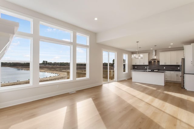 14984 Fillmore St, West Olive, MI 49460 - kitchen featuring wall chimney exhaust hood, freestanding refrigerator, a chandelier, a water view, and backsplash
