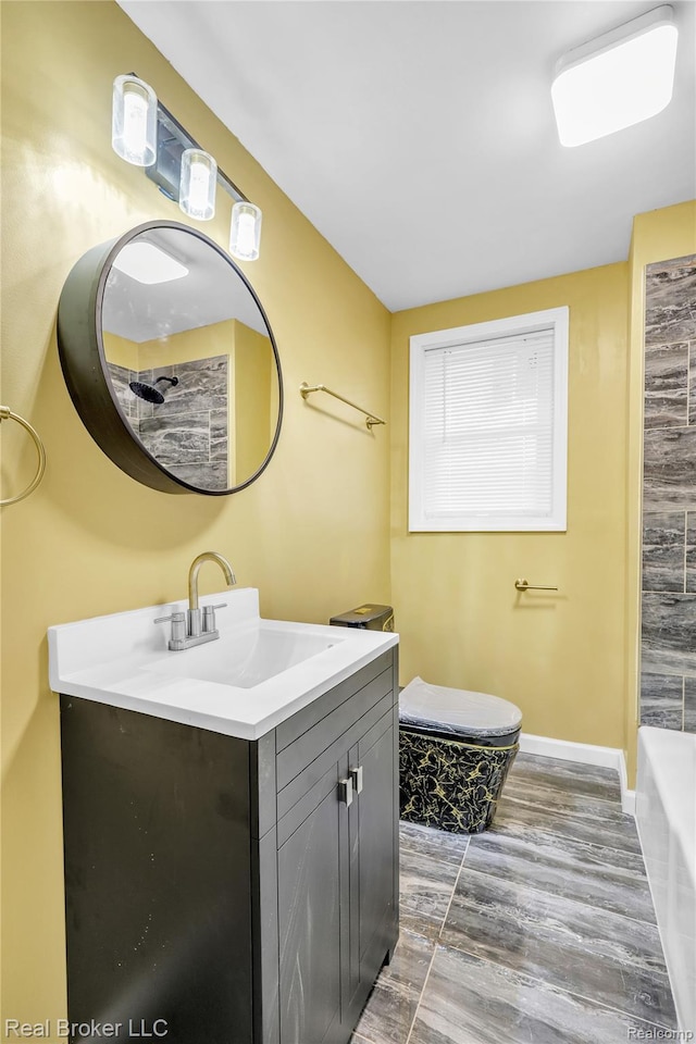 2089 Kenneth St, Burton, MI 48529 - bathroom featuring vanity, wood finished floors, a bath, baseboards, and toilet