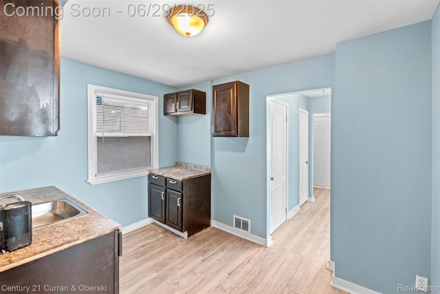 4220 Webb St, Detroit, MI 48204 - kitchen with dark brown cabinets, light wood-style flooring, and light countertops