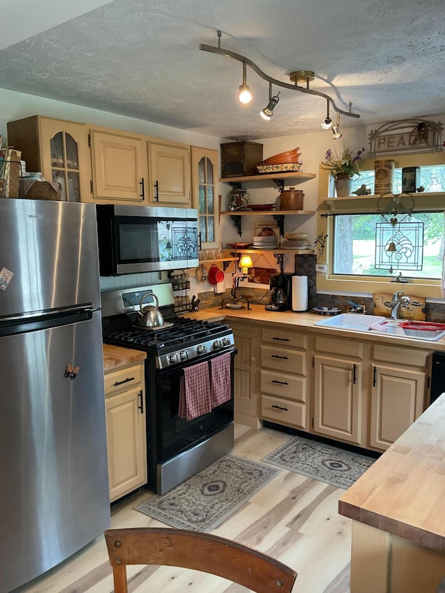 50 N Sprague St, Coldwater, MI 49036 - kitchen with appliances with stainless steel finishes, a sink, light wood finished floors, glass insert cabinets, and a textured ceiling