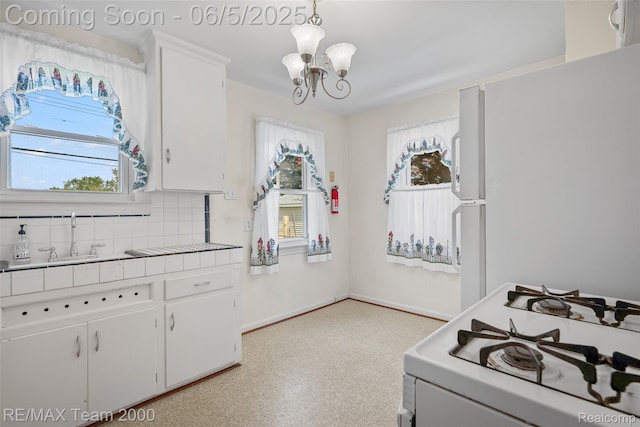 2922 Bailey Ave, Wyandotte, MI 48146 - kitchen featuring gas range gas stove, a chandelier, white cabinetry, and tasteful backsplash