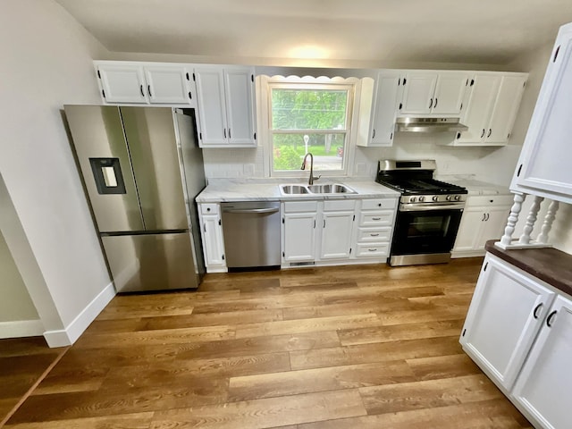 4408 Arbor Dr, Okemos, MI 48864 - kitchen featuring stainless steel appliances, a sink, light wood-style floors, white cabinets, and under cabinet range hood