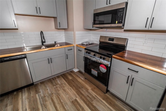 519 S Elm St, Lapeer, MI 48446 - kitchen with appliances with stainless steel finishes, butcher block countertops, gray cabinets, backsplash, and wood finished floors