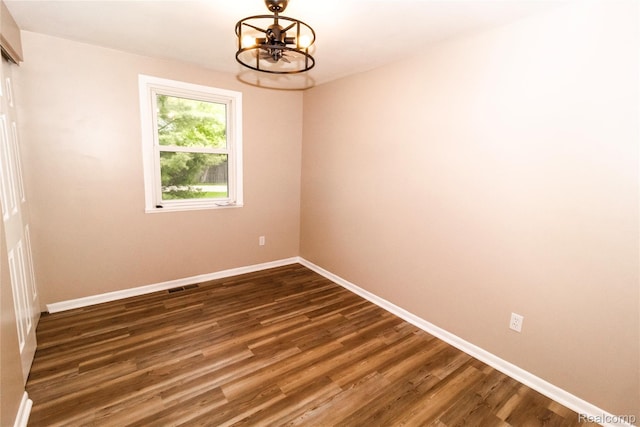 519 S Elm St, Lapeer, MI 48446 - spare room with a chandelier, baseboards, and dark wood-style floors
