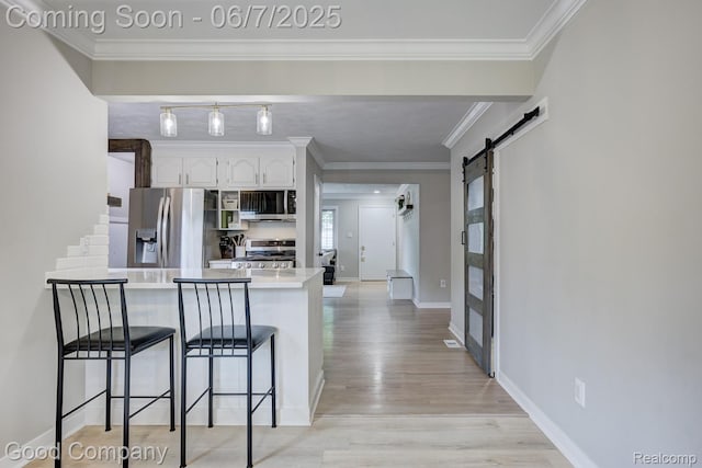 4511 Rosewold Ave, Royal Oak, MI 48073 - kitchen with appliances with stainless steel finishes, a peninsula, a barn door, a kitchen breakfast bar, and white cabinets