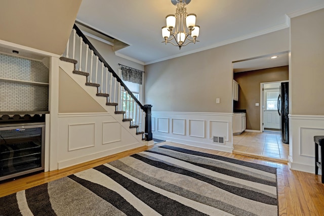 350 N Broadway St, Lake Orion, MI 48362 - stairway with wood finished floors, a chandelier, beverage cooler, a wainscoted wall, and crown molding