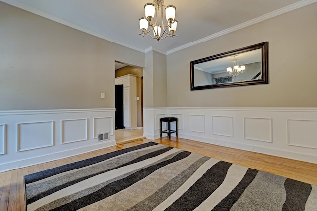 350 N Broadway St, Lake Orion, MI 48362 - unfurnished room featuring a chandelier, light wood-style floors, crown molding, and wainscoting