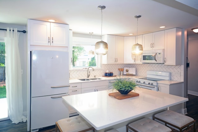 222 S Park St, Zeeland, MI 49464 - kitchen featuring white appliances, a sink, a breakfast bar area, white cabinets, and tasteful backsplash