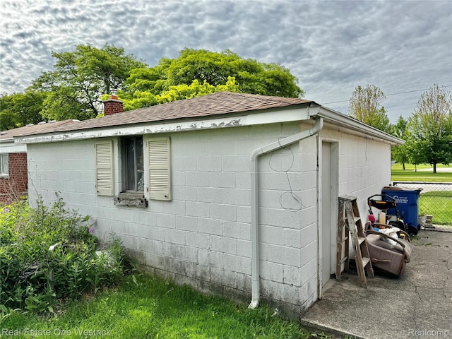 32008 Bunert Rd, Warren, MI 48088 - view of side of property with concrete block siding, a chimney, and roof with shingles