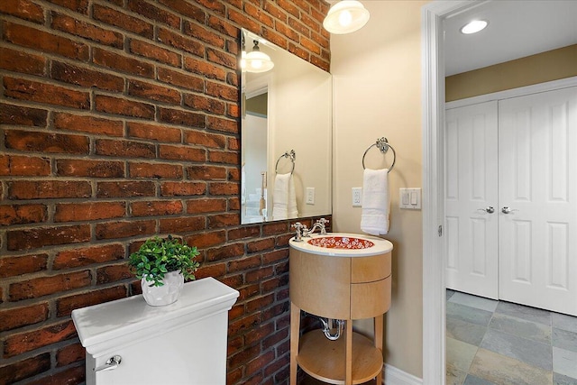 998 Eagle Ave, Ann Arbor, MI 48103 - half bathroom featuring brick wall, toilet, and stone finish floors