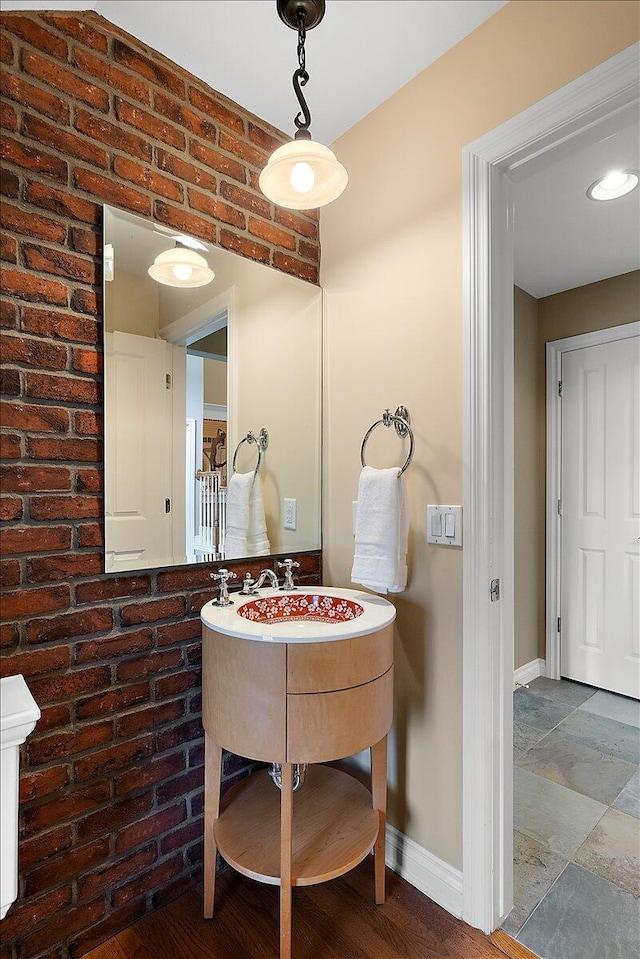 998 Eagle Ave, Ann Arbor, MI 48103 - bathroom featuring baseboards, brick wall, and stone tile flooring