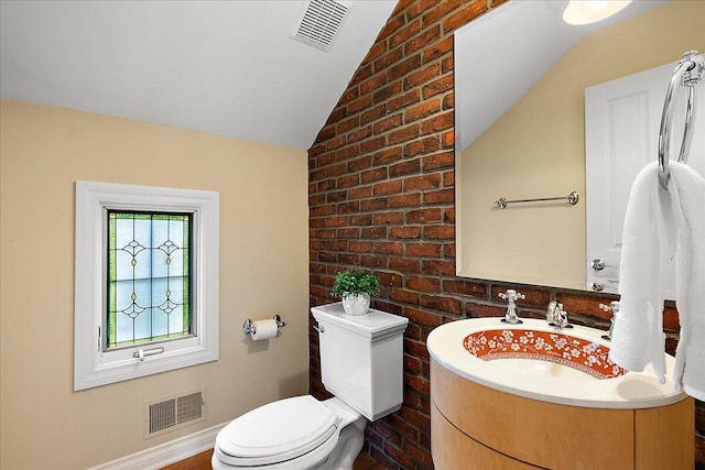 998 Eagle Ave, Ann Arbor, MI 48103 - half bathroom featuring toilet, vanity, lofted ceiling, brick wall, and baseboards