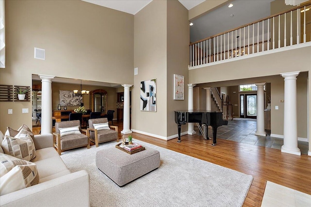 998 Eagle Ave, Ann Arbor, MI 48103 - living room featuring baseboards, a towering ceiling, wood finished floors, ornate columns, and stairs