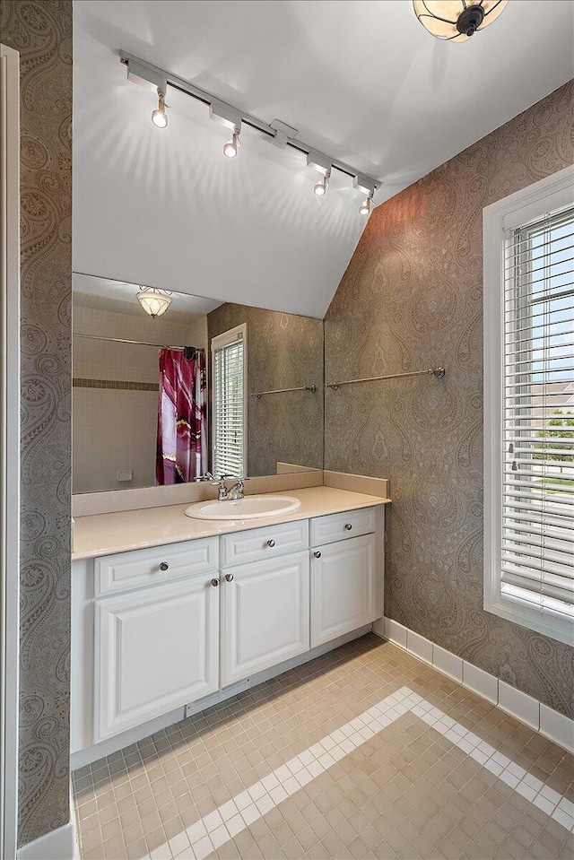 998 Eagle Ave, Ann Arbor, MI 48103 - bathroom with rail lighting, vanity, baseboards, wallpapered walls, and lofted ceiling