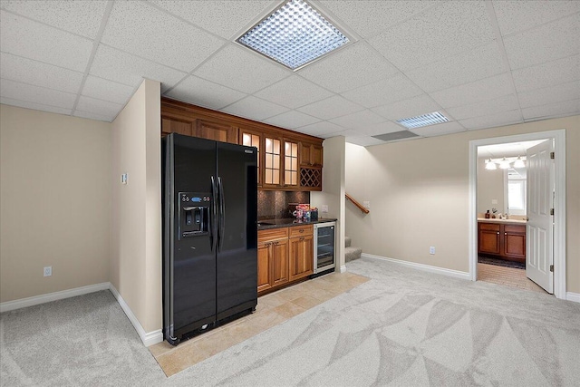 998 Eagle Ave, Ann Arbor, MI 48103 - kitchen with black fridge with ice dispenser, beverage cooler, light colored carpet, brown cabinetry, and a paneled ceiling