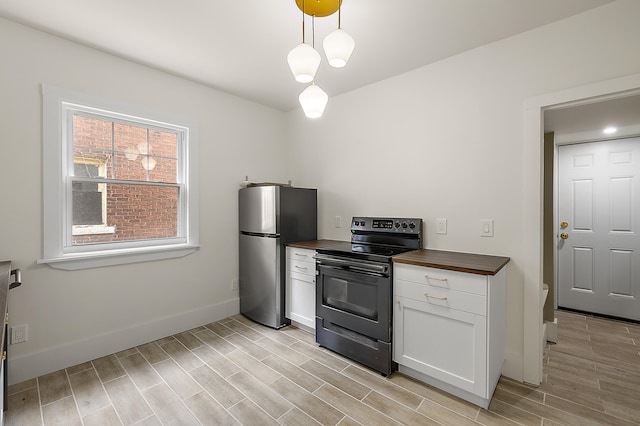 1174 Taylor St, Detroit, MI 48202 - kitchen featuring black range with electric stovetop, freestanding refrigerator, wooden counters, light wood finished floors, and white cabinetry