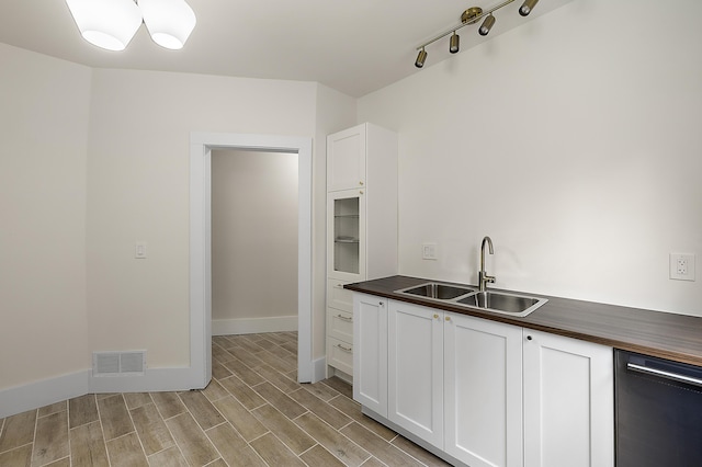 1174 Taylor St, Detroit, MI 48202 - kitchen with a sink, dishwashing machine, white cabinetry, light wood-style floors, and baseboards