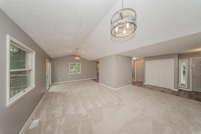 242 S Wallace Blvd, Ypsilanti, MI 48197 - unfurnished living room featuring a chandelier, light colored carpet, baseboards, vaulted ceiling, and a textured ceiling