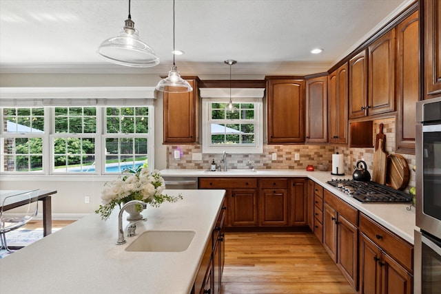 71438 Forest Eagle Ln, Niles, MI 49120 - kitchen featuring a sink, light countertops, light wood-style floors, pendant lighting, and ornamental molding