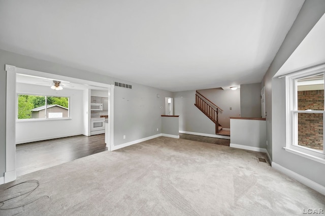 5662 Caren Dr, Ypsilanti, MI 48197 - unfurnished living room with carpet floors, baseboards, stairs, and a ceiling fan