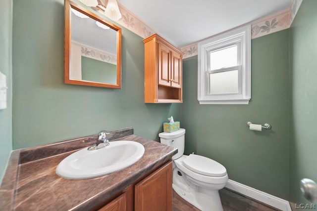 5662 Caren Dr, Ypsilanti, MI 48197 - half bath featuring toilet, vanity, wood finished floors, and baseboards