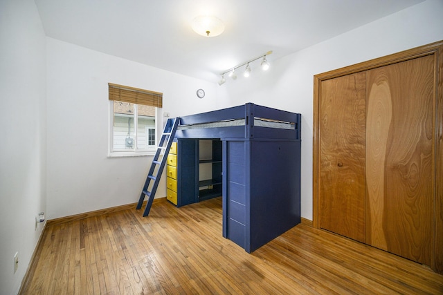 111 N Maple Rd, Saline, MI 48176 - unfurnished bedroom with hardwood / wood-style flooring, track lighting, baseboards, and a closet