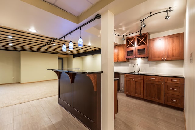 3329 Craig Rd, Ann Arbor, MI 48103 - kitchen featuring a breakfast bar area, a sink, dark countertops, brown cabinets, and glass insert cabinets