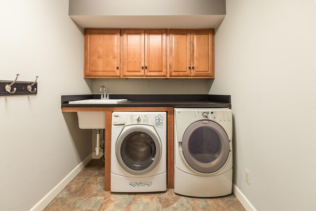 3329 Craig Rd, Ann Arbor, MI 48103 - laundry area featuring washer and clothes dryer, cabinet space, baseboards, and light stone finish floors