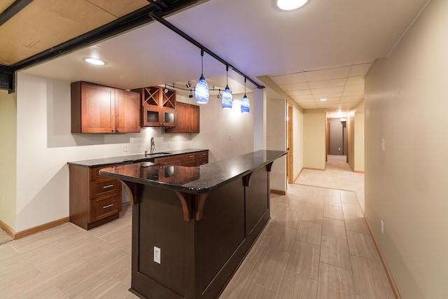 3329 Craig Rd, Ann Arbor, MI 48103 - kitchen featuring a sink, brown cabinetry, baseboards, a kitchen bar, and glass insert cabinets