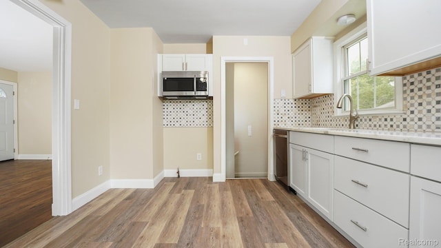 1139 S 7th St, Ann Arbor, MI 48103 - kitchen featuring appliances with stainless steel finishes, light wood-style flooring, white cabinets, and backsplash
