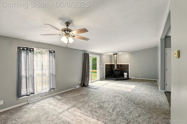 10900 Tuttlehill Rd, Milan, MI 48160 - unfurnished living room with a wood stove, a ceiling fan, carpet, a textured ceiling, and baseboards