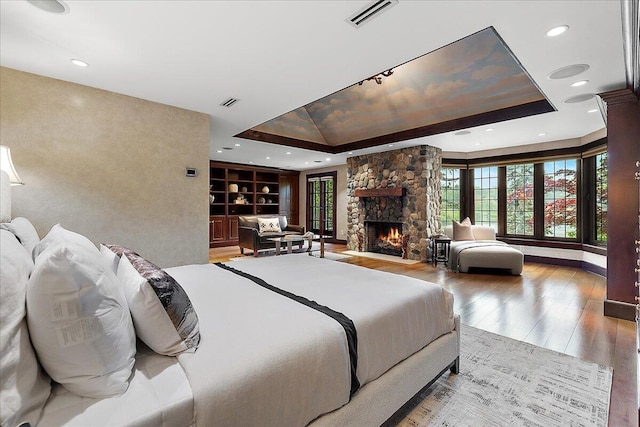 490 E Long Lake Rd, Bloomfield Hills, MI 48304 - bedroom with wood-type flooring, a stone fireplace, a tray ceiling, recessed lighting, and rail lighting