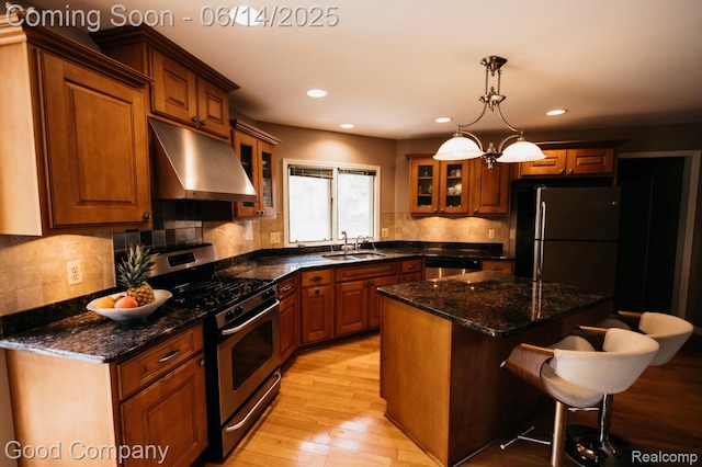 515 Oakbridge Dr, Rochester, MI 48306 - kitchen featuring under cabinet range hood, appliances with stainless steel finishes, a kitchen bar, light wood finished floors, and glass insert cabinets