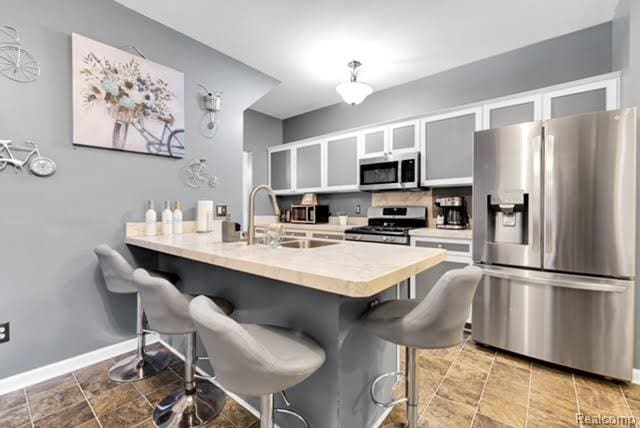32051 W Cranston St, New Haven, MI 48048 - kitchen featuring appliances with stainless steel finishes, a sink, a kitchen breakfast bar, and a peninsula