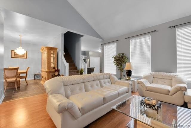 32051 W Cranston St, New Haven, MI 48048 - living room featuring stairs, high vaulted ceiling, a chandelier, wood finished floors, and baseboards