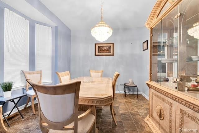32051 W Cranston St, New Haven, MI 48048 - dining room with stone finish floors, a chandelier, and baseboards
