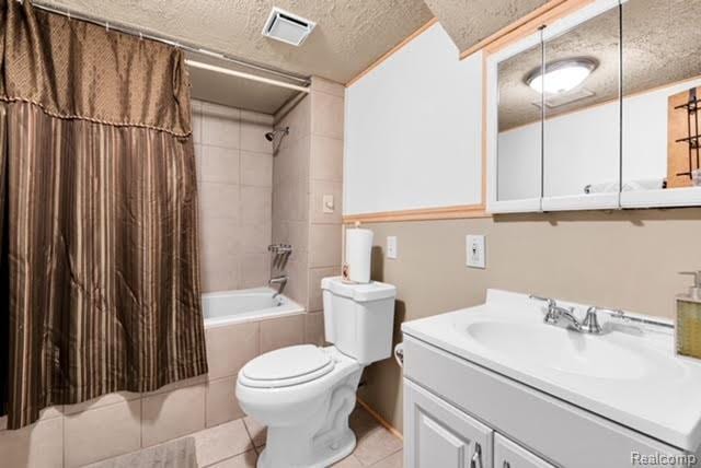 32051 W Cranston St, New Haven, MI 48048 - full bath with a textured ceiling, shower / bath combo, vanity, toilet, and tile patterned flooring