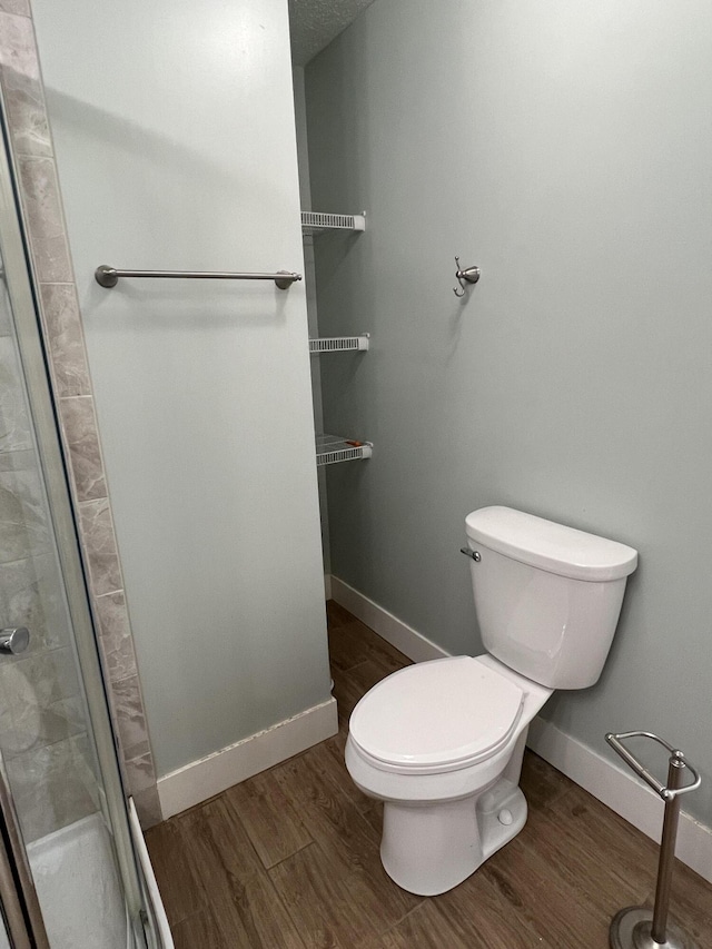 1302 Barnes St, Albion, MI 49224 - bathroom featuring toilet, a stall shower, wood finished floors, and baseboards