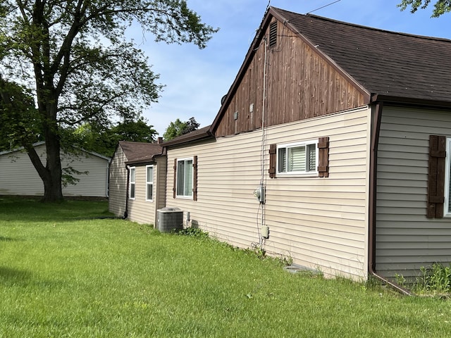 1302 Barnes St, Albion, MI 49224 - view of home's exterior featuring central AC unit, a shingled roof, and a yard