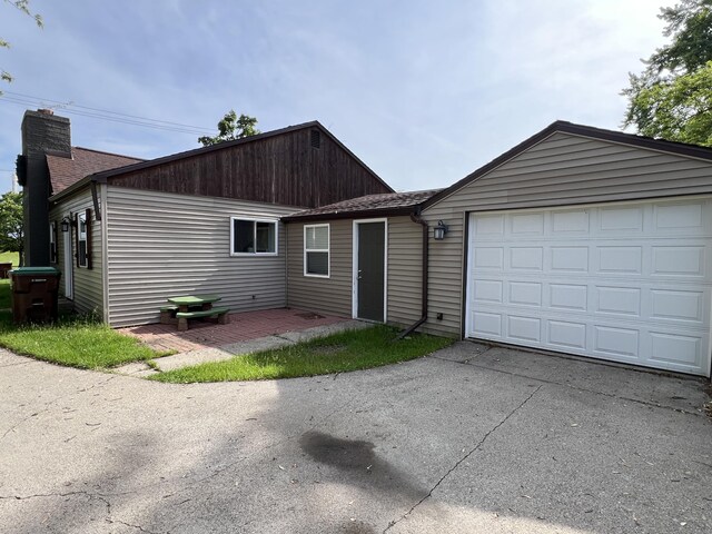 1302 Barnes St, Albion, MI 49224 - view of front of house featuring asphalt driveway, an attached garage, and a chimney