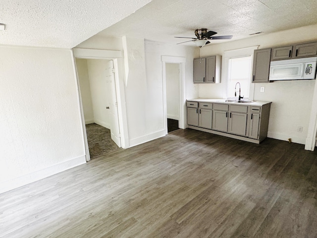 2513 5th St, Muskegon, MI 49444 - kitchen with white microwave, a sink, gray cabinets, a ceiling fan, and dark wood-style flooring