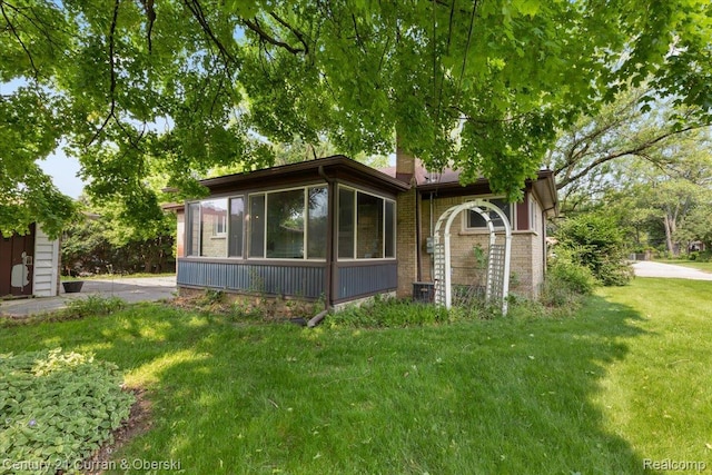 3183 Mildred St, Wayne, MI 48184 - view of front of house with a sunroom, a front yard, and brick siding
