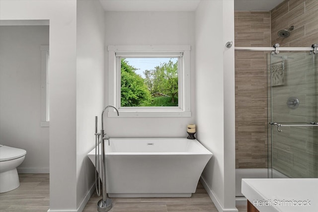 1200 Iroquois Trl, Hastings, MI 49058 - bathroom with baseboards, a freestanding tub, a shower stall, and wood finished floors